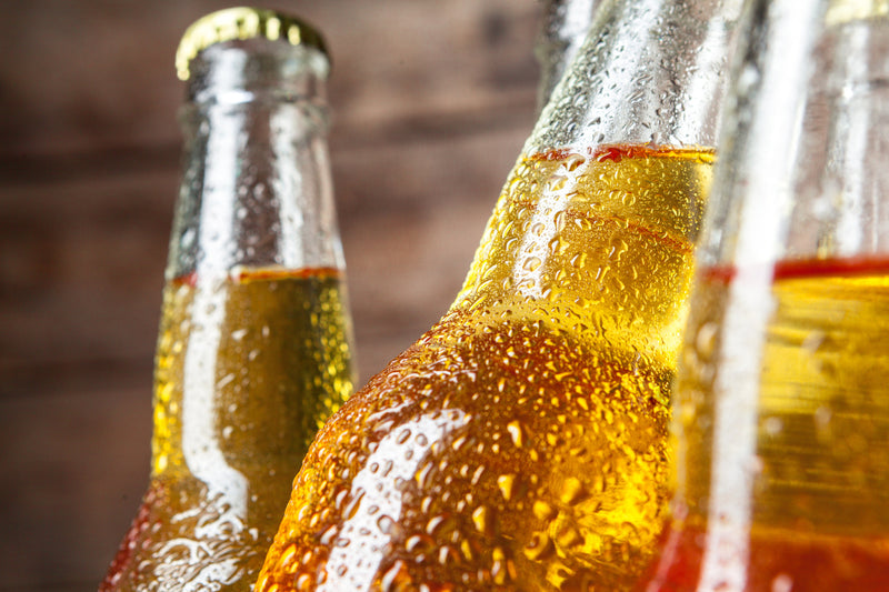 Three bottles of beer with condensation on a wooden background
