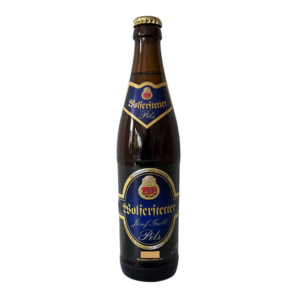 A single bottle of Wolferstetter Brau Pils dark beer in a dark brown glass bottle with a gold cap and a blue, gold, and red label, shown against a plain white background.